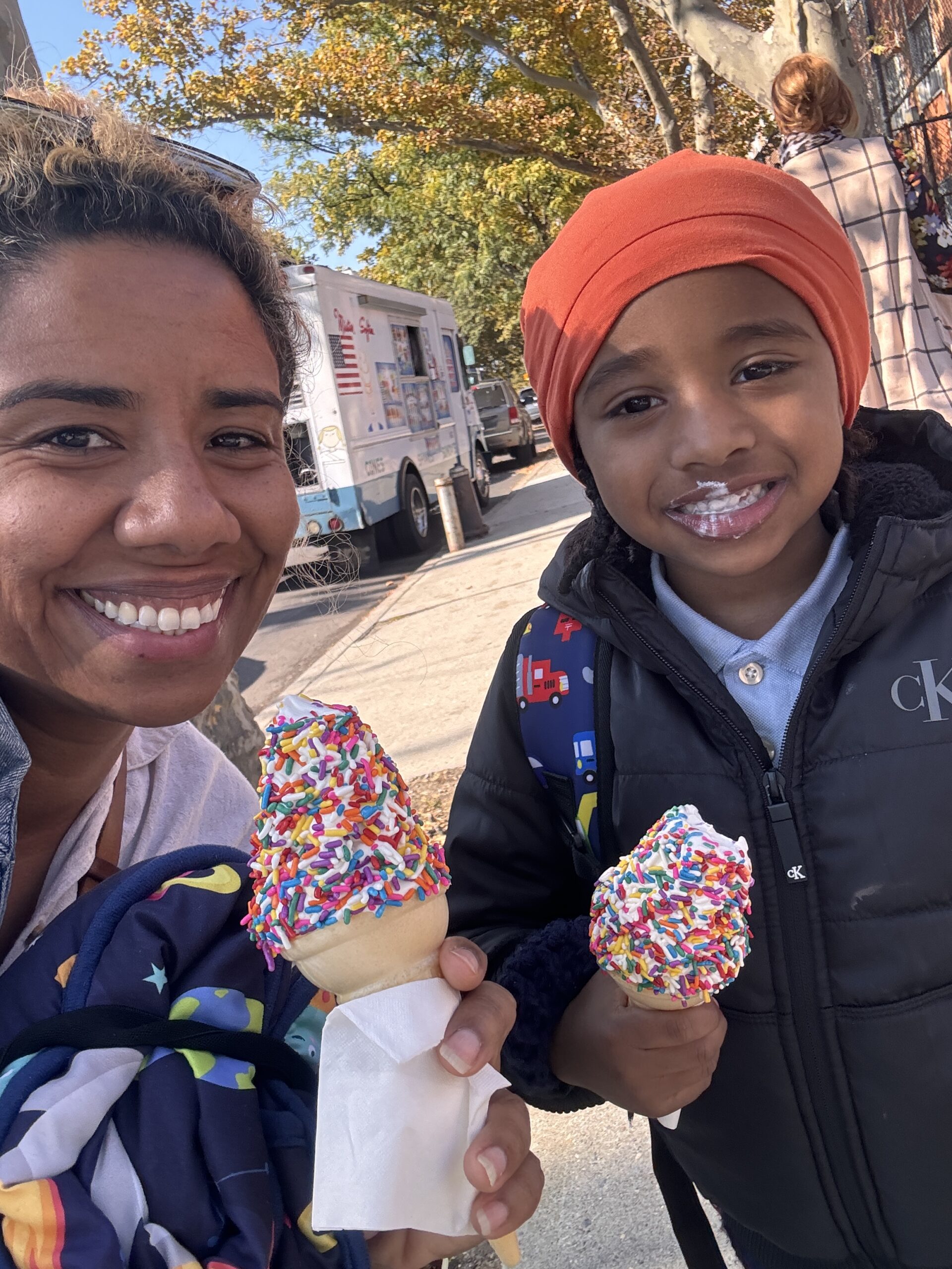 Mother and young son smiling with ice cream cones covered in sprinkles